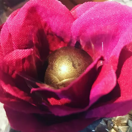 Bombom dourado entre pétalas de papel cor-de-rosa